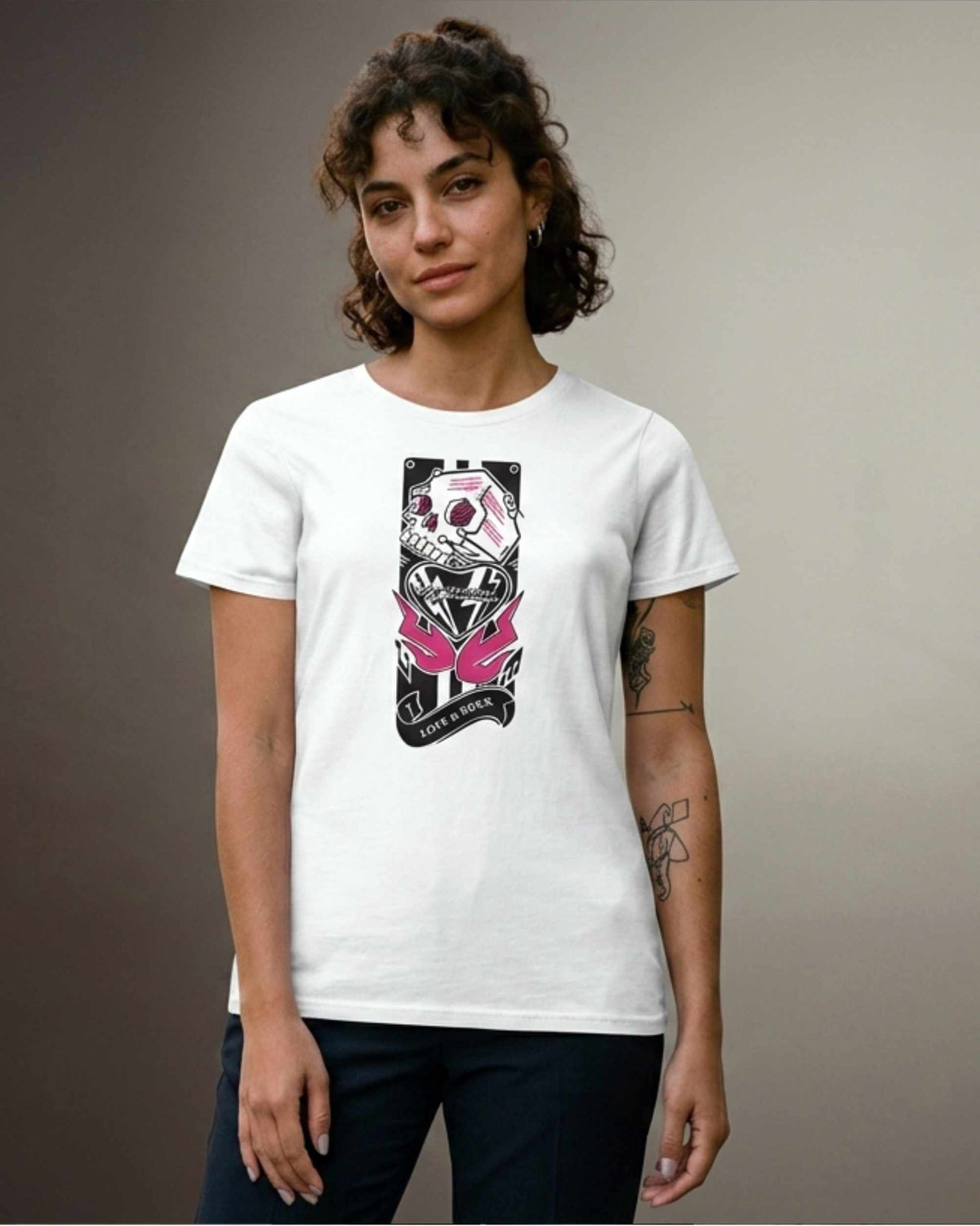 A woman modeling a white short-sleeve crewneck t-shirt with a black and pink graphic print on the front, paired with dark blue jeans, set against a neutral gray studio background.