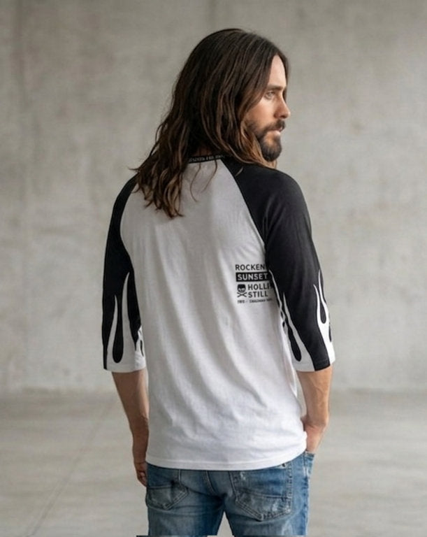 Back view of a man wearing a white and black three-quarter sleeve raglan shirt featuring black sleeves, flame-like graphic details, and a small ROCKEN graphic on the upper back.