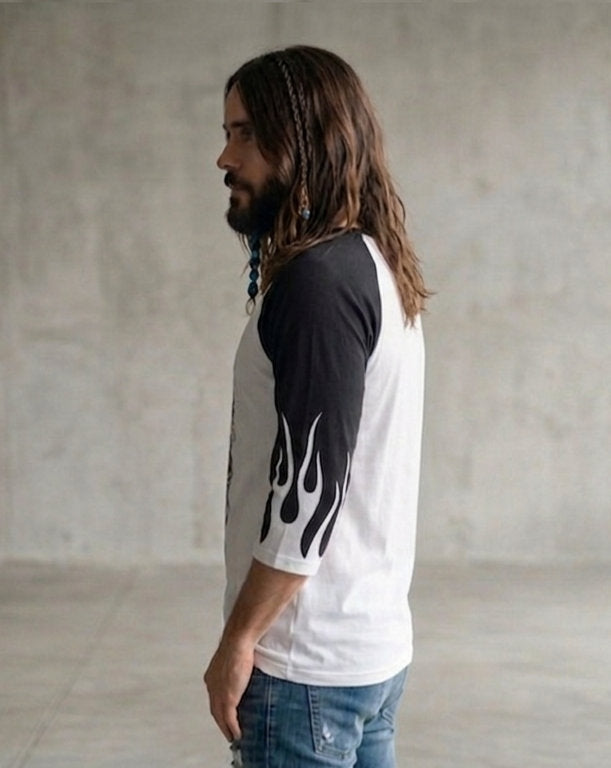 Side view of a man wearing a white and black three-quarter sleeve raglan shirt featuring black sleeves and flame-like graphic details.