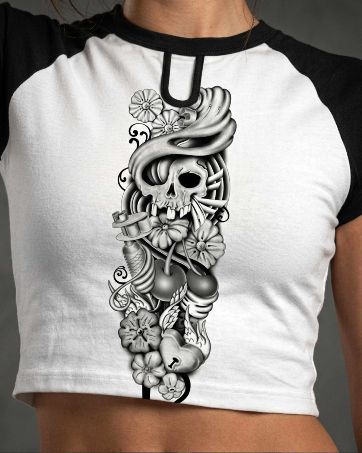 Close-up of a black and white cropped raglan shirt featuring the Sakura Revolution artwork with a skull, flowers, flowing hair, and intricate ornamental details.