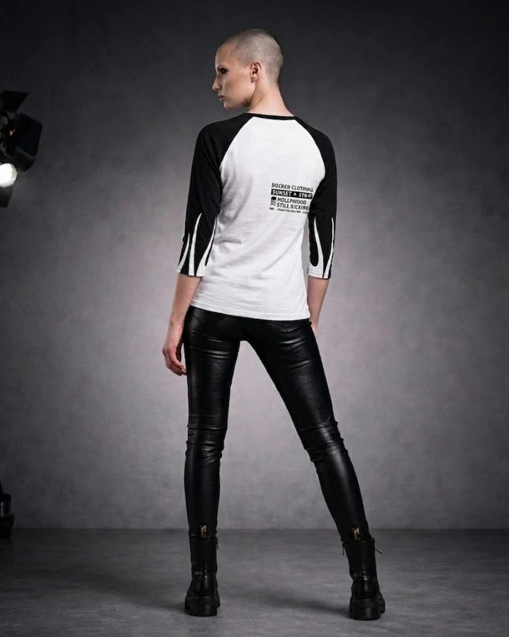 Back view of a woman wearing a white and black three-quarter sleeve raglan shirt with black sleeves and a small ROCKEN graphic on the upper back.
