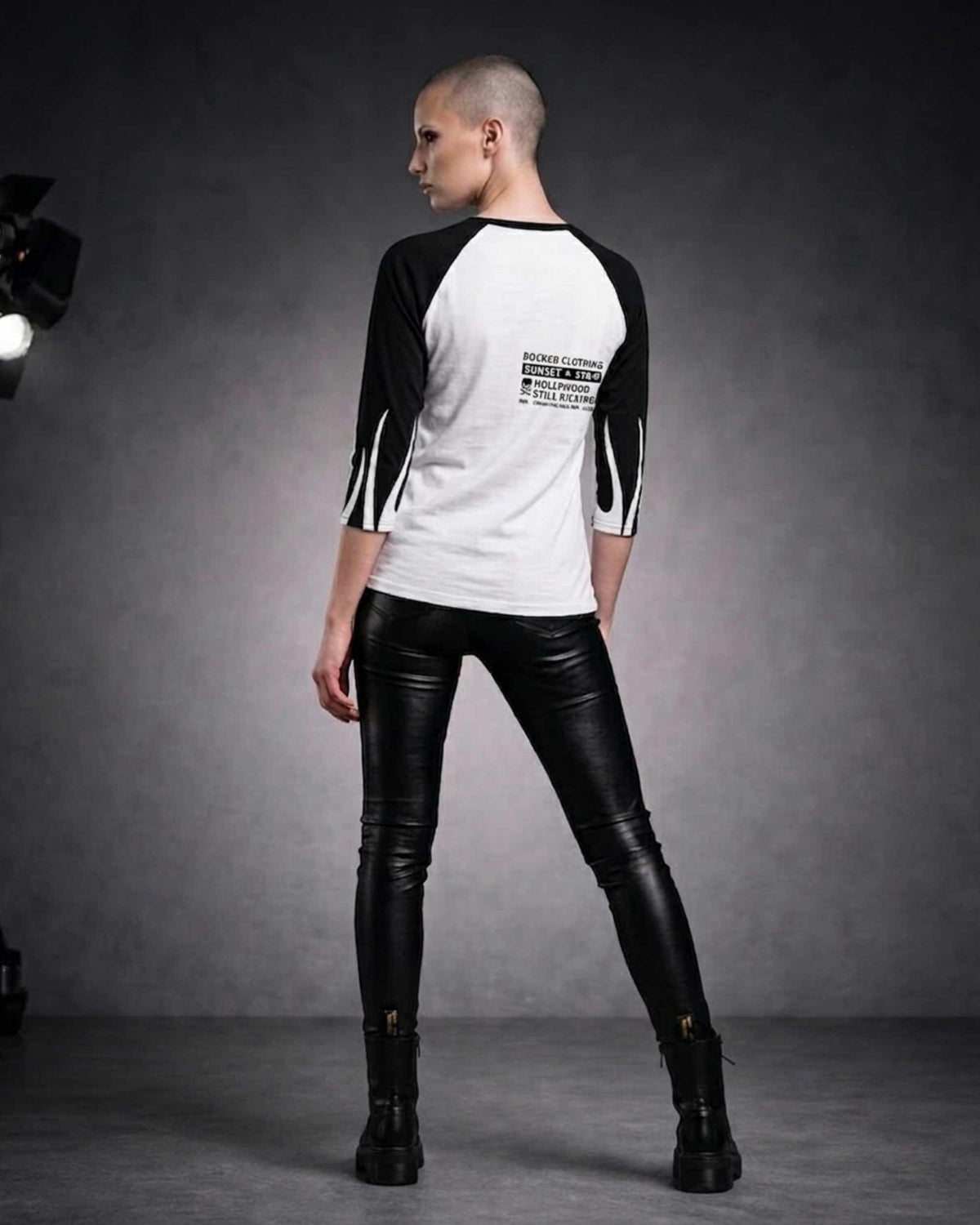 Back view of a woman wearing a white and black three-quarter sleeve raglan shirt with black sleeves and a small ROCKEN graphic on the upper back.